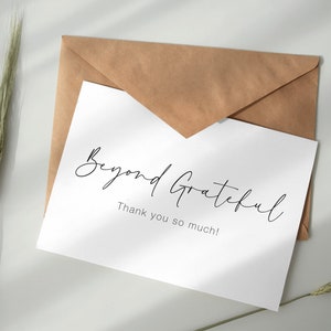 Può includere: Un biglietto bianco con il testo "Beyond Grateful" scritto in corsivo nero. Sotto il testo c'è la frase "Thank you so much!" in un carattere nero più piccolo.