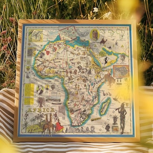 May include: A framed vintage map of Africa with a colourful design and detailed illustrations of animals, people, and landmarks. The map is titled "AFRICA" and includes text in multiple languages.