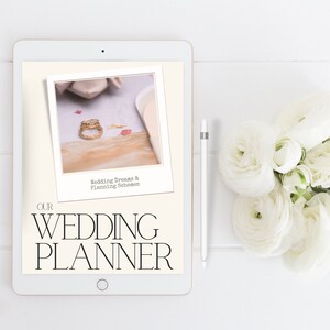 May include: A white tablet with a digital wedding planner on the screen. The screen shows a photo of two gold rings on a white surface with the text "Wedding Dreams & Planning Schemes". The text "OUR WEDDING PLANNER" is displayed on the screen.