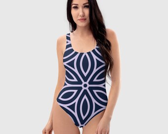 May include: A navy blue one-piece swimsuit with a geometric pattern in a lighter shade of purple. The pattern is a repeating design of overlapping circles and ovals.