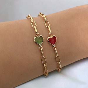 May include: Two gold chain bracelets with heart charms. One charm is green and the other is red.