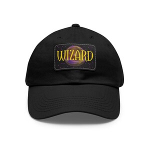 Könnte beinhalten: Eine schwarze Baseballkappe mit einem Patch, der eine lila und goldene Kugel mit dem Wort "WIZARD" in gelben Buchstaben zeigt.
