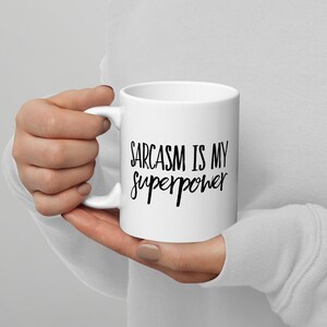 May include: White ceramic coffee mug with black text that reads "Sarcasm is my superpower".