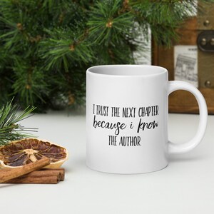 May include: White ceramic coffee mug with black text that reads "I trust the next chapter because I know the author".