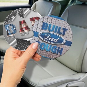 May include: Two round car coasters with a silver and black diamond plate design. One coaster features the text "Dad #MAN #MYTH" with an American flag design. The other coaster features the text "Built Tough Dad" with a blue Ford logo.