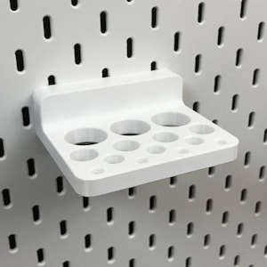 May include: White plastic pegboard organizer with multiple round holes for holding small items.