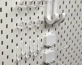 Paquete de ganchos y soportes Skadis de IKEA: ganchos pequeños, ganchos grandes y soportes de alambre doble, en PETG negro mate o blanco, resistentes y robustos.