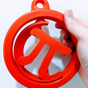 May include: A bright red 3D printed ornament shaped like the mathematical symbol pi. The ornament has a hole at the top for hanging.