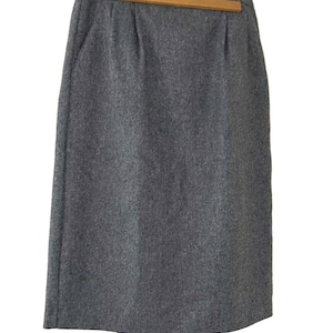 May include: A gray wool skirt with a straight silhouette and a simple design.