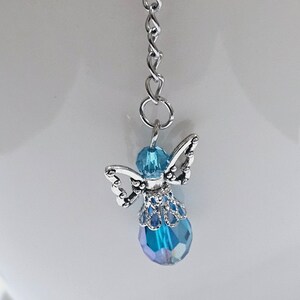 Op de afbeelding: Een zilveren ketting met een blauwe kristallen engelbedel. De engel heeft zilveren vleugels en een blauw kristallen lichaam.