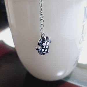 Könnte beinhalten: Eine weiße Keramiktasse mit einem schwarzen und weißen Tupfen-Hunde-Tee-Infuser, der am Rand hängt. Die Tasse hat den Text "My Love &" auf der Seite.