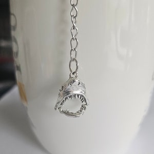 May include: Silver tea infuser shaped like a shark's open mouth with a chain attached.