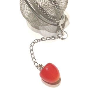 May include: A silver tea infuser with a red ball on the end of the chain.