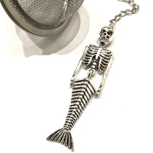 May include: Silver skeleton mermaid tea infuser with a mesh ball attached to a chain.