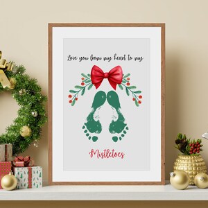 May include: A framed print with a green footprint design and a red bow. The text reads "Love you from my heart to my mistletoes".