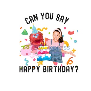 Puede incluir: Una niña con una camisa rosa y un mono azul sonríe mientras sostiene un pastel de cumpleaños colorido. Una marioneta de peluche rosa con un gorro de fiesta sostiene el pastel con ella. El texto "Can you say Happy Birthday?" está escrito en letras negras sobre un fondo blanco.