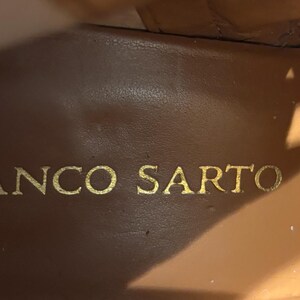 May include: Close-up of the interior of a brown leather shoe. The brand name "FRANCO SARTO" is embossed in gold lettering on the insole. The leather has a smooth, worn appearance.