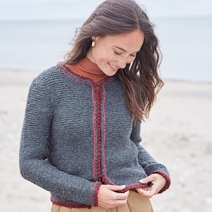 May include: A gray knitted cardigan with a red and brown trim around the neckline, cuffs, and hem.