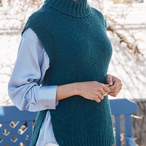 Puede incluir: Un suéter de punto azul teal sin mangas con cuello alto.