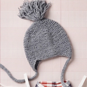 May include: Gray knitted baby hat with a pom-pom on top and ties that can be tied under the chin.