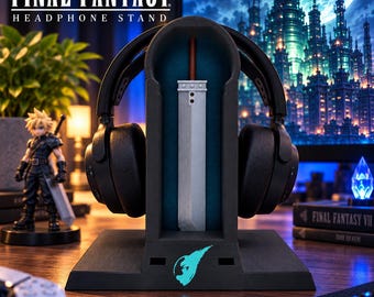 May include: A black Final Fantasy headphone stand featuring a central Buster Sword replica and a glowing blue logo on the base. The stand is designed to hold over-ear headphones, with a dark blue interior panel and a sturdy rectangular base.