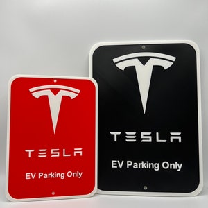May include: Two signs with white borders and white text on a red and black background. The signs feature the Tesla logo and the text "Tesla EV Parking Only".