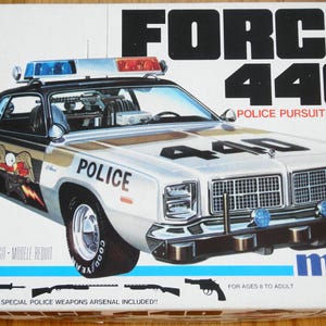 Puede incluir: Una caja de modelo para un "Force 440 Police Pursuit Vehicle". La caja presenta un coche de policía blanco y plateado con "POLICE" impreso en el lateral. La caja también incluye el texto "1/25 Model Kit" y "Special Police Weapons Arsenal Included!!"