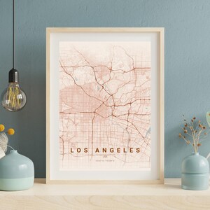 Könnte beinhalten: Ein gerahmter Druck mit einer Karte von Los Angeles, USA, in einem warmen, erdigen Farbschema. Die Karte zeigt das Straßennetz der Stadt. Der Text "LOS ANGELES" ist am unteren Rand des Drucks zu sehen.