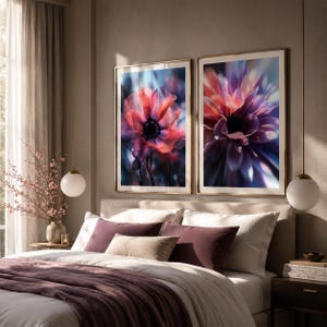 Könnte beinhalten: Zwei gerahmte Kunstdrucke mit Blumenmotiven. Die Drucke zeigen Nahaufnahmen von Blumen in Rot-, Lila- und Blautönen. Die Blumen haben ein weiches, verschwommenes Aussehen. Die Rahmen sind goldfarben. Die Drucke werden über einem Bett mit einer lila Decke und Kissen ausgestellt.
