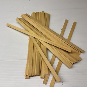 Può includere: Un mucchio di bastoncini per l'artigianato in legno naturale, larghi circa 6 mm e lunghi 15 cm. I bastoncini sono disposti in modo casuale, con alcuni che si sovrappongono.