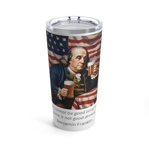 May include: A stainless steel tumbler with a white background and a graphic of Benjamin Franklin holding two glasses of beer in front of an American flag. The text "There cannot be good living where there is not good drinking. Benjamin Franklin" is printed below the graphic.