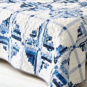 Może przedstawiać: Biała kołdra z niebiesko-białym wzorem. Kołdra jest wykonana z kwadratów i prostokątów, a wzór to połączenie motywów kwiatowych i geometrycznych.