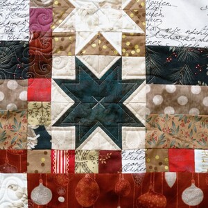 Könnte beinhalten: Ein Patchwork-Deckenstück mit einer Vielzahl von Stoffen, darunter ein dunkelblauer Stern, ein weißer Stern und ein rot-weiß gestreiftes Stoff. Die Decke besteht aus vielen verschiedenen Quadraten und Rechtecken, und die Stoffe sind alle zusammengenäht, um ein einzigartiges und interessantes Design zu schaffen.