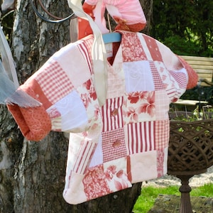 Könnte beinhalten: Ein Patchwork-Shirt aus rosa und weißem Stoff mit Blumenmuster. Das Shirt hat einen Knopfkrag und kurze Ärmel.