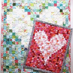 Könnte beinhalten: Zwei handgefertigte Quilts. Der größere Quilt hat ein Patchwork-Design mit Quadraten in verschiedenen Farben und Mustern, darunter Blumen- und geometrische Drucke. Der kleinere Quilt zeigt eine Herzform in Rot- und Rosatönen. Beide Quilts haben dekorative Bordüren.