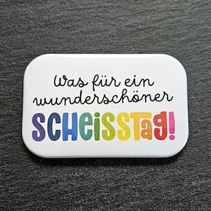 Könnte beinhalten: Ein weißer rechteckiger Magnet mit dem Text "Was für ein wunderschöner SCHEISSTAG!" in Regenbogenfarben.