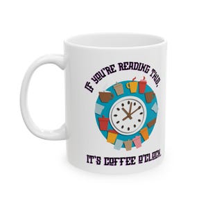 Puede incluir: Taza de café de cerámica blanca con asa. La taza presenta un diseño de reloj con tazas de café y el texto "If you're reading this, it's coffee o'clock" en morado y negro.