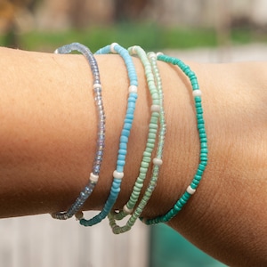 Könnte beinhalten: Eine weiße Keramik-Tasse mit schwarzem Henkel und dem Text "But First, Coffee" in schwarzer, fetter Schrift. Die Tasse steht auf einer weißen Oberfläche.