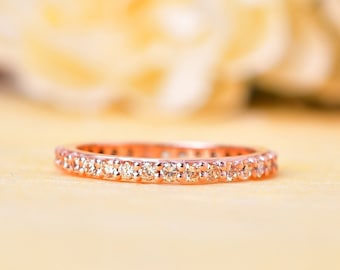 May include: A delicate rose gold band ring with a row of small, sparkling diamonds.