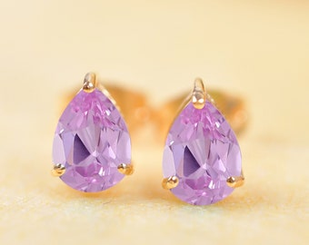 May include: A pair of gold earrings with teardrop-shaped purple gemstones.