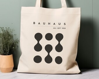Puede incluir: Una bolsa de lona blanca con texto negro y un diseño gráfico. El texto dice "Bauhaus Juli - Sept 1923".