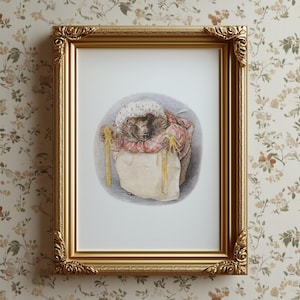 Puede incluir: Una impresión enmarcada con una ilustración en acuarela de un erizo con un vestido y un gorro a cuadros rojos y blancos, sosteniendo un saco beige con asas amarillas. La impresión está en un marco dorado ornamentado.