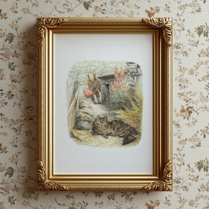 Könnte beinhalten: Ein gerahmter Druck mit einer skurrilen Illustration einer Katze, die sich in der Nähe einer Steinmauer ausruht, und eines Kaninchens, das einen Apfel trägt. Der Druck befindet sich in einem goldenen, verzierten Rahmen, der dem Kunstwerk einen Hauch von Eleganz verleiht. Der Hintergrund ist eine florale Tapete.