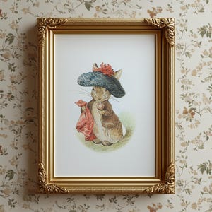 Puede incluir: Impresión enmarcada con una ilustración de un conejo con sombrero azul con flor roja, chaqueta marrón y tela roja. El marco dorado tiene detalles ornamentales en las esquinas.