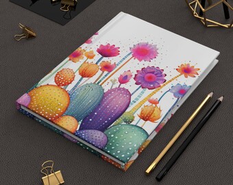 Könnte beinhalten: Ein Hardcover-Notizbuch mit einem lebendigen Blumen- und Kaktusdesign. Das Cover zeigt farbenfrohe Illustrationen von Kakteen und Blumen in Rosa-, Lila-, Orange- und Blautönen. Goldene und schwarze Bleistifte und Büroklammern sind ebenfalls zu sehen.