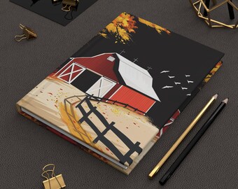 Könnte beinhalten: Ein Hardcover-Journal mit einer ländlichen Scheunen-Szene. Es zeigt eine rote Scheune, weiße Türen und einen schwarzen Zaun. Das Cover-Design umfasst Herbstlaub und Vögel vor schwarzem Hintergrund. Goldene und schwarze Bleistifte und Büroklammern sind ebenfalls zu sehen.