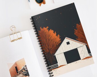 May include: A spiral-bound notebook featuring an autumn scene with a white barn, orange trees, and a dark sky. The notebook is open on a white surface with a gold paper clip and sunglasses.