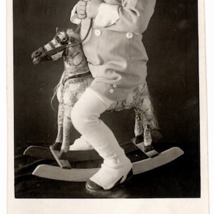 Photo of a child on a rocking wooden horse toy. Original vintage black and white photograph that also reflects children&#39;s fashion, year 1937