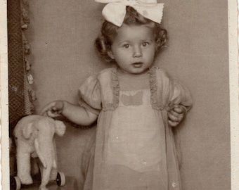 Fotografía vintage de 1947 de una bebé niña: Niña con un elefante de juguete, retrato de estudio.