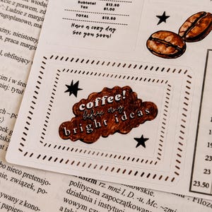 May include: A sticker sheet with coffee-themed designs. Includes coffee beans, stars, and a cloud-shaped sticker with the text "coffee! before my bright ideas". The sheet also features a receipt and the phrase "Have a cozy day, See you soon!"